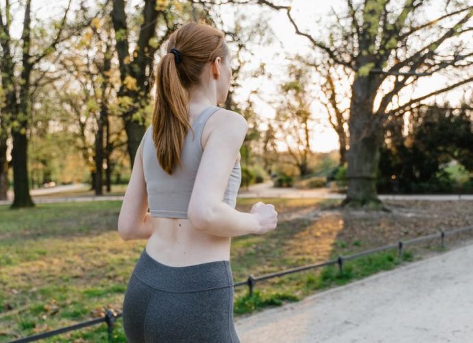 A woman jogs in a park during sunset, enjoying an outdoor fitness routine.
