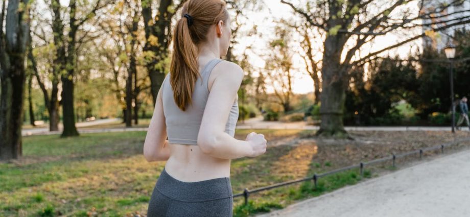 A woman jogs in a park during sunset, enjoying an outdoor fitness routine.